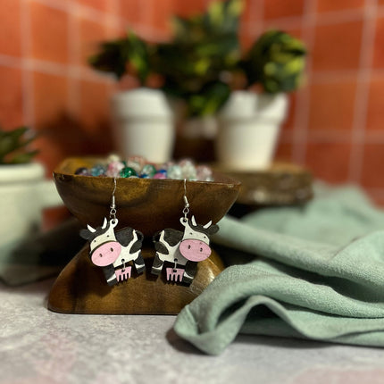 Pair of hand-painted birchwood cow earrings with pink udders and sterling silver fishhook wires