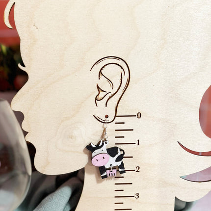 Cow earring shown on wood earring size chart displaying approximate 2 inch drop length