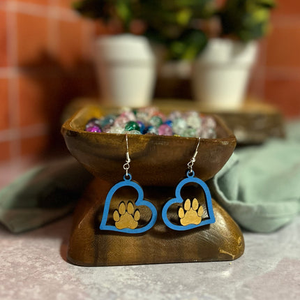 Blue hand-painted birchwood paw heart earrings with sterling silver fishhook wires, displayed on a wooden bowl stand